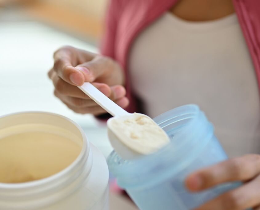 Woman in kitchen measuring powder supplement